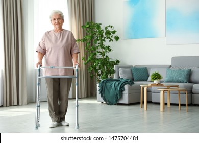 Elderly woman using walking frame indoors. Space for text