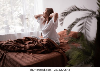 Elderly woman waking up in morning, sits on her bed and stretches after good night sleep, good mood, lady enjoying start of new day. Copy space - Powered by Shutterstock