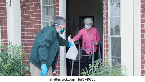 An elderly woman with a walker who is at high risk because of the coronavirus COVID19 gets meals or groceries delivered to her house by a volunteer working with a benevolent organization. - Shutterstock ID 1696740631