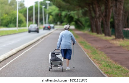 elderly woman walking pushing trolley bag - Powered by Shutterstock