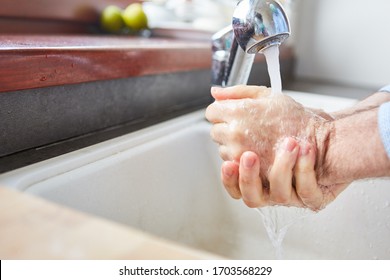 Elderly woman washing hands with soap and water due to Covid-19 coronavirus epidemic - Powered by Shutterstock