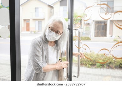 An elderly woman wearing a mask opening the door - Powered by Shutterstock