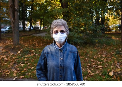 Elderly Woman Wearing A Medical Face Mask, Outside. Portrait Of A Pensioner With Glasses On A Walk.