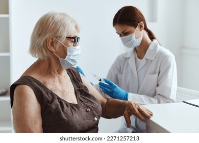 elderly woman wearing a medical mask sitting next to the nurse covid-19 passport - Powered by Shutterstock