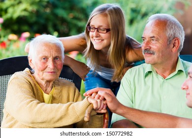 Elderly woman welcoming her family - son and granddaughter in the garden of the nursing home.