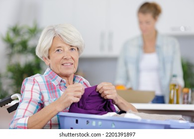 Elderly Woman In Wheelchair Holding A Laundry Basket