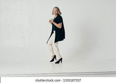 An Elderly Woman In White Shoes And A Sweater Is Dancing On A Light Background In Full Growth                           