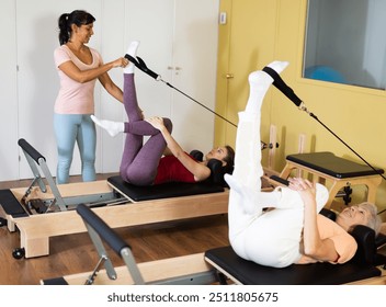 Elderly woman and young girl practicing exercises on Pilates reformer. Concept of pilates as physical therapy alternative for injury rehab - Powered by Shutterstock