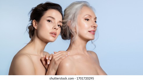 Elderly woman and young woman with perfect skin portrait. Young daughter standing behind older mother putting hand on arm looking at camera. Different age generation family bonding. Beautiful people - Shutterstock ID 1701720295