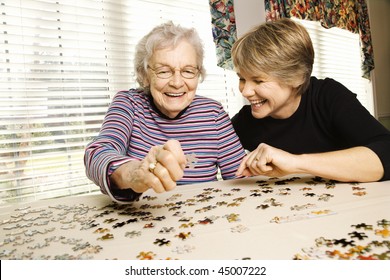 Elderly woman and a younger woman work on a jigsaw puzzle.  Horizontal shot. - Powered by Shutterstock