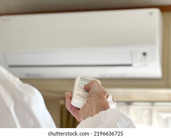 Elderly Woman's Hand Pointing The Remote Control To The Air Conditioner