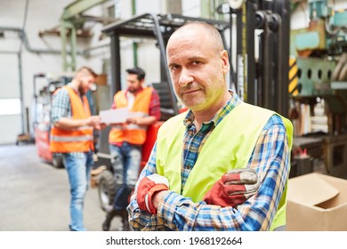 Elderly worker as a foreman in the warehouse of the metal factory with his arms crossed