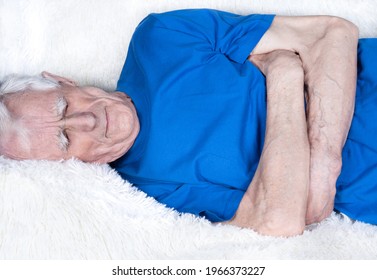 Eldery Man Laying On White Sofa And Suffering From Stomachache. Male Hands Holding Stomach.