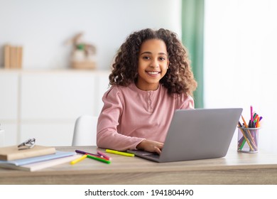 E-Learning. African american girl studying on laptop computer learning at home and smiling to camera