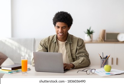 E-learning concept. African American teenager studying online on laptop computer at home. Black youth using PC to make home assignment, talk to his college teacher or fellow students on webcam