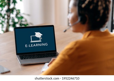 E-learning concept. Over shoulder view of african american girl on laptop screen. Female student with sits at work desk at home, studies remotely. Online education, webinar, lecture