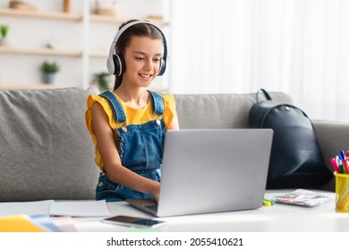 E-learning concept. Smiling teenager in headset studying online on laptop computer at home. Happy youth using PC to make home assignment, typing on keyboard, chatting with friends or doing homework - Shutterstock ID 2055410621