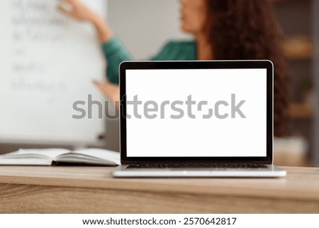 E-learning Course, Remote Education. Selective focus on blank white laptop screen on table, mock up. Lady teacher shooting video lecture using computer having chat with students, explaining material