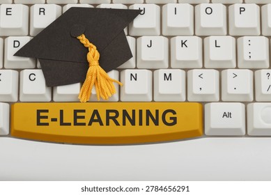 E-learning text with a grad cap on white computer keyboard for online degrees and remote learning
