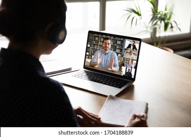 E-learning via virtual application, videocall video conferencing activity, colleagues working together concept. Pc screen view over woman shoulder, listen tutor gain new knowledge noting information - Shutterstock ID 1704188839