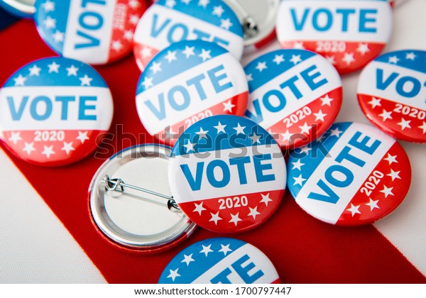 Election 2020 in the USA. Variety Of\
Presidential Election Buttons on American\
flag