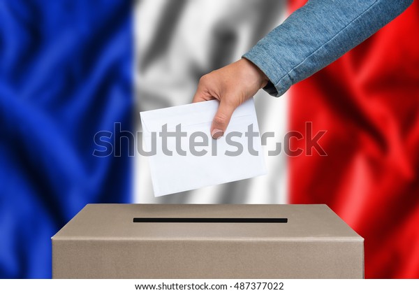 Election in France. The hand\
of woman putting her vote in the ballot box. French flag on\
background.