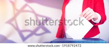 Election in Israel. Hand of a woman putting her vote in the ballot box. Waved Israel flag on background.