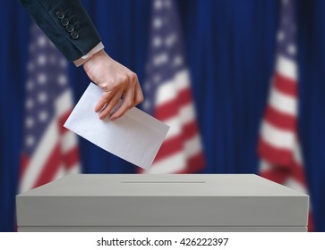 Election in United States of America. Voter holds envelope in hand above vote ballot. USA flags in background. Democracy concept. - Shutterstock ID 426222397