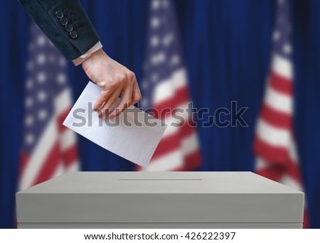 Election in United States of America. Voter holds envelope in hand above vote ballot. USA flags in background. Democracy concept.
