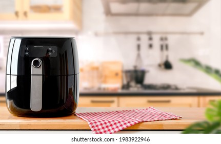 An electric Air Fryer on table with blurred kitchen background.  Lifestyle of new normal cooking.  - Shutterstock ID 1983922946