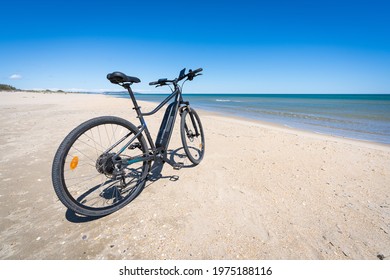 An Electric Bicycle On A White Sand Beach With A Blue Sea