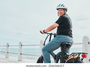 Electric bike, portrait or travel with a senior man on a promenade, riding eco friendly transport by the beach. Sustainability, cycling or mock up with a mature male tourist by the seaside for a ride - Powered by Shutterstock