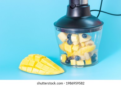 Electric Blender With Fruit Inside And Mango On A Blue Background Close-up.