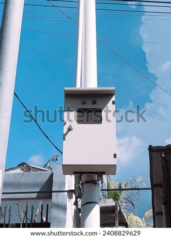 electric box on electric pole with a bright blue sky background and cables wires