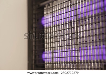 Electric bug zapper featuring glowing purple UV tubes and a metal safety grid. Ideal for commercial or domestic pest control and insect elimination.