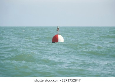 Electric buoy in the sea with green island in background.