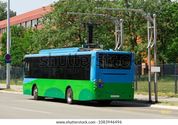 Electric bus at a\
stop is charged by\
pantograph
