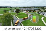 Electric buses with battery status icon. Aerial of eco-friendly public transport of students in USA. EV graphic charging icon with yellow buses leaving American school