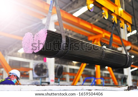 Electric Cable Hoist , heavy hoist iron hook lifting of round steel bars and place on a truck at warehouse.