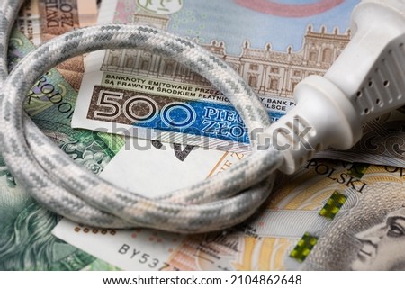 Electric cable with socket and many Polish banknotes. Rise of electricity price in Poland. Photo taken under artificial, soft light
