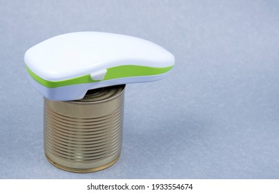Electric can opener and canned good isolated on gray background
