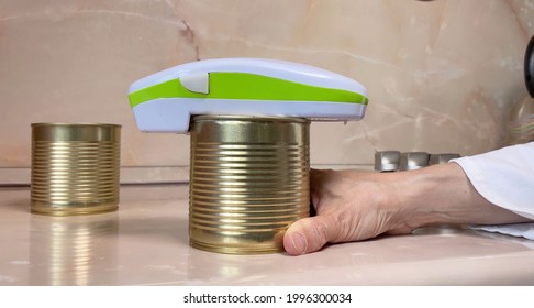 Electric can opener and canned goods on kitchen table