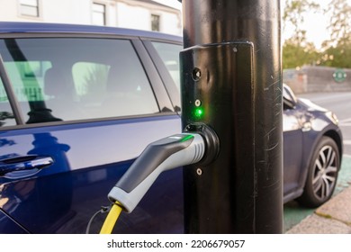 Electric car being charged from a charging point on a street light post. - Shutterstock ID 2206679057