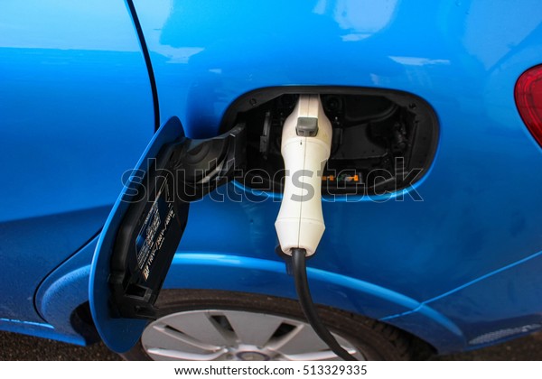 Electric Car Being Charged. Electric car\
charging station. Close up of the power supply plugged into an\
electric car being\
charged.