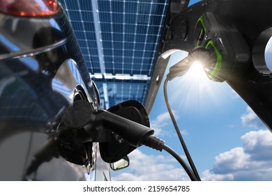 Electric Car Is Charged From A Charging Station At Carport That Takes Energy From Solar Panels. Close Up