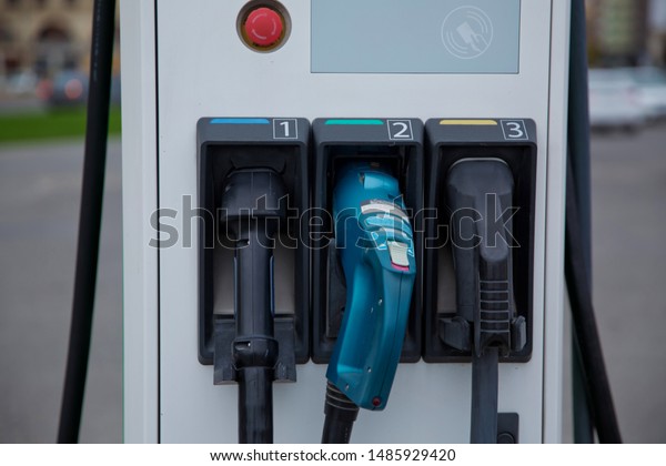 Electric car charger . The panel with two pistols\
for charging electric vehicles close-up. Electric charge station\
for eco car with charger to recharge electricity into vehicle on\
city street outdoor