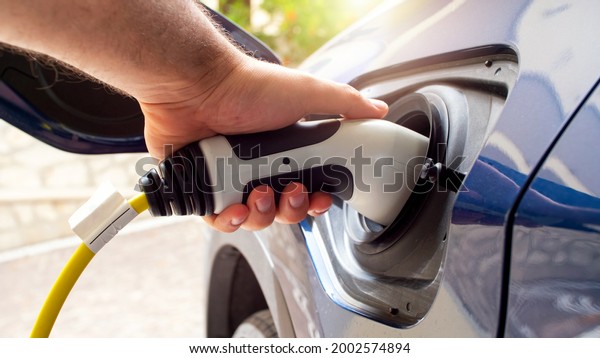The electric car charger\
plugged in to the socket.The modern electric car charging the\
battery.