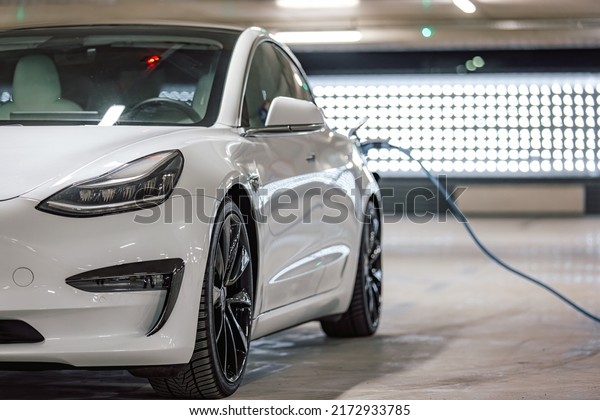 Electric car charger plugged in a vehicle socket\
in the parking garage