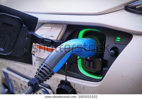 Electric car charging its battery with
natural landscape, for green environment, ecology, sustainability,
clean air, future. Bolzano, Italy - July
2021