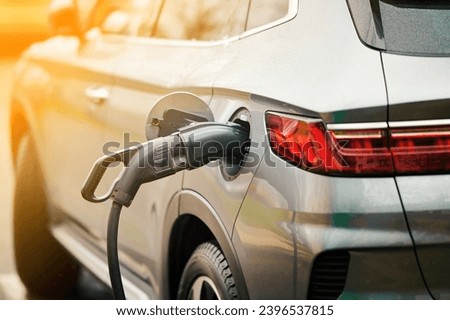 Electric car charging in the city, sunny background. Charging port of an electric car. Charging plug of an electric car, charging socket. Electric transport. EV car